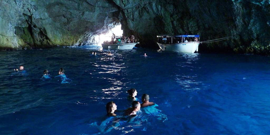 Blue Cave Dubrovnik — electric-blue interior on Koločep island, guests swimming at the cave entrance